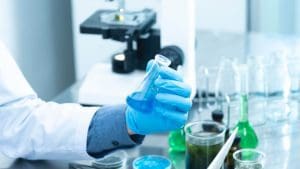 In einem Labor hält ein Wissenschaftler ein Reagenzglas mit blauer Flüssigkeit in der Hand